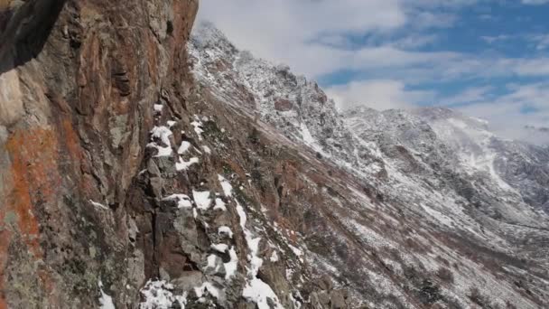 Vista aérea del tramo cercano de la cámara junto a una pared de roca en lo alto de las montañas a principios de primavera hierba verde y nieve en las laderas de las montañas — Vídeo de stock