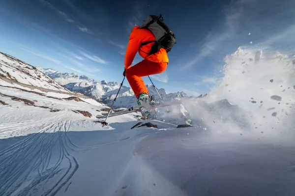 Close-up Atleta masculino esquiador salta de uma encosta coberta de neve contra o pano de fundo de uma paisagem montanhosa de montanhas cobertas de neve em um dia ensolarado. O conceito de esportes de inverno grande ângulo — Fotografia de Stock