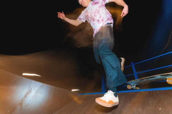 Un joven patinador hace el truco de deslizarse por la noche en un skatepark. El concepto de ocio nocturno y cultura juvenil por la noche — Foto de Stock