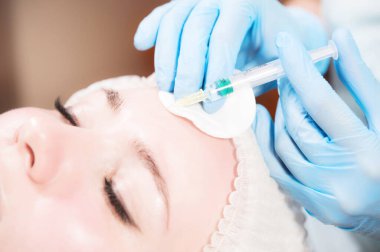 Kadın bir güzellik uzmanı kozmetik ofisinde kadın bir müşteriye iğne yapıyor. Yenilenme için kozmetik prosedürleri