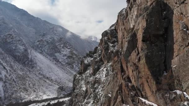 Vue aérienne d'une travée étroite à côté des rochers dans les montagnes à travers la gorge en dessous de laquelle passe la piste d'asphalte — Video