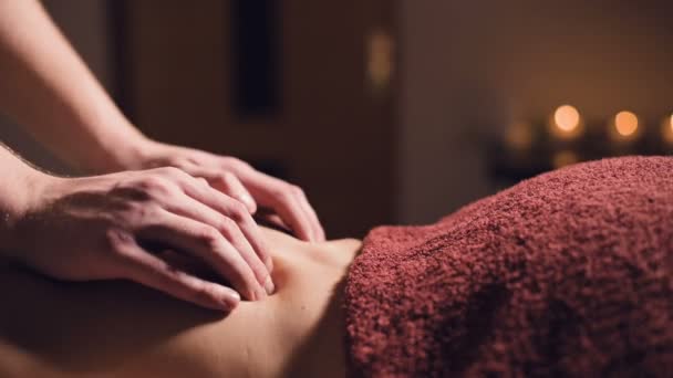 Młody mężczyzna masażysta wykonuje profesjonalną klientkę masażu w profesjonalnym salonie masażu z zapalonymi świecami w ciemnym pokoju — Wideo stockowe
