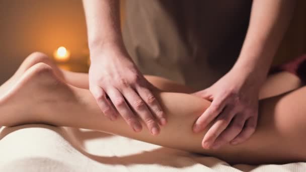 Detailní záběr na masáž lýtkového svalu rukou. Profesionální masérka masíruje ženskou nohu v kanceláři krásným světlem — Stock video