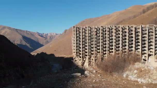 Estruturas de proteção de concreto de ferro com vista aérea contra deslizamentos de lama e avalanches. Estrutura protectora parcialmente destruída. homem de jaqueta laranja sobe a altitude sem seguro — Vídeo de Stock