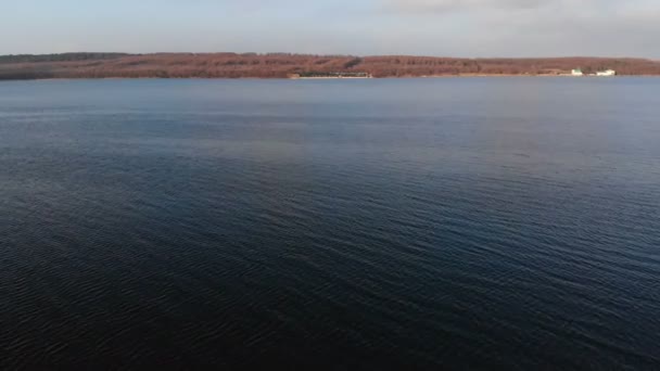 Uma vista aérea de um drone voador baixo sobre a superfície lisa do drone à noite após o pôr do sol. Vídeo de fundo com corpo natural local de água — Vídeo de Stock