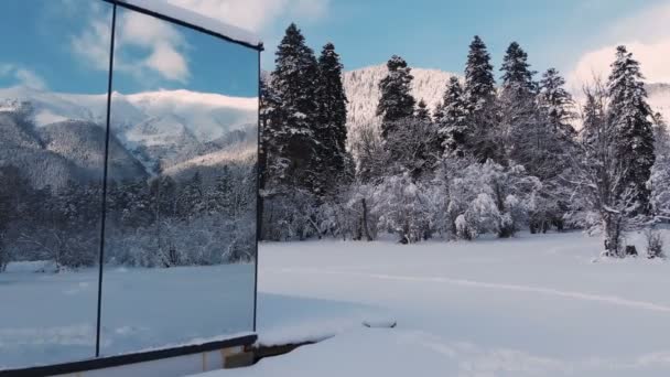 Veduta aerea di un'innovativa casa high-tech con pareti specchiate in mezzo a una foresta invernale in montagna. Il concetto di ecoturismo in montagna. Architettura moderna nelle riserve naturali — Video Stock