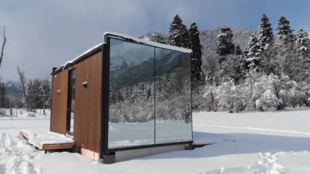Luftaufnahme eines innovativen Hightech-Hauses mit verspiegelten Wänden inmitten eines Winterwaldes in den Bergen. Das Konzept des Ökotourismus in den Bergen. Moderne Architektur in Naturschutzgebieten — Stockvideo