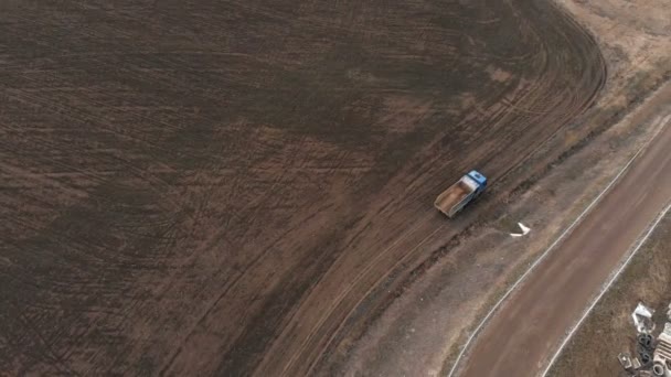 Veduta aerea di un camion scarico vuoto che percorre una strada sterrata. Il concetto di lavori di costruzione e smaltimento dei rifiuti di costruzione — Video Stock