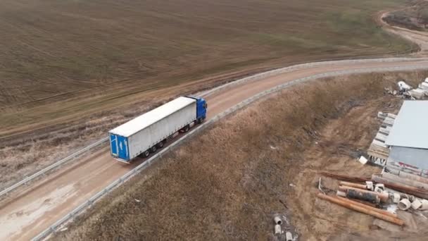 Veduta aerea di un grande camion con un rimorchio che percorre una strada sterrata alla ricerca di un posto per un'inversione a U nelle vicinanze di una strada suburbana. — Video Stock