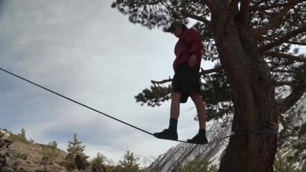 एक युवा उत्तरी काकेशस के पहाड़ों में एक स्लैकलाइन पर टीयर करता है . — स्टॉक वीडियो