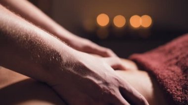 Genç bir erkek masör, profesyonel bir masaj salonunda, karanlık bir odada mum yakarak müşteri kızı beceriyor.