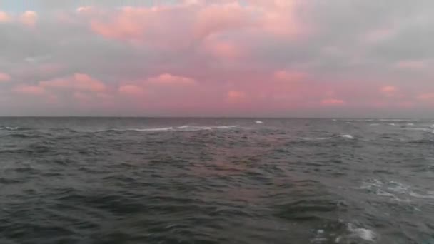En flygbild av flygningen över den baltiska havskusten på kvällen strax efter solnedgången. Begreppet en video av bakgrunden av havet från en fågel-eye vy rosa moln på himlen — Stockvideo