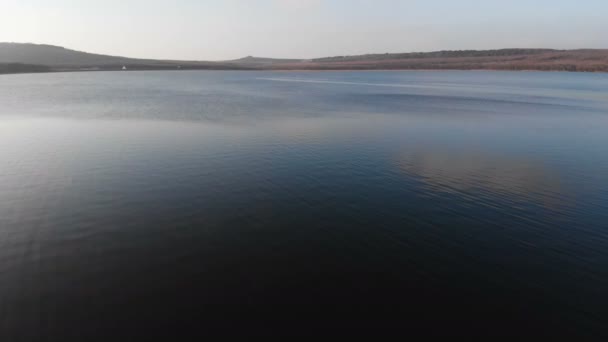 Letecký pohled z nízko letícího dronu na hladký povrch dronu večer po západu slunce. Pozadí videa s místním přirozeným tělem vody — Stock video