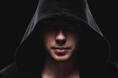 Siyah arka planda koyu kapüşonlu cesur bir adamın yakın plan portresi. Sırların gizliliği kavramı ve hükümetten saklanan insanlar. Hackerlar ve hırsızlar. Alçak tuş