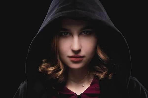 Retrato de cerca de una chica joven y reservada con una capucha oscura sobre un fondo negro. El concepto de secreto de secretos y personas que se esconden del gobierno. — Foto de Stock