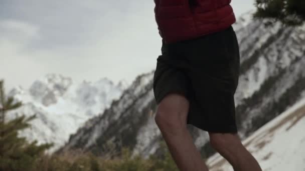 Ein junger Mann in kurzer Jacke und Schirmmütze mit Sonnenbrille balanciert am Nachmittag auf einer gespannten Slackline im Nadelwald. Outdoor-Sport- und Freizeitkonzept — Stockvideo