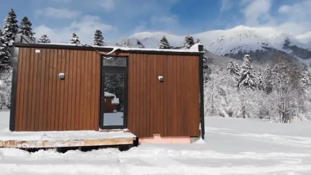 산 속의 겨울 숲 속에 벽이 거울로 가려져 있는 혁신적 인 하이테크 주택을 공중에서 본 것이다. 산에서의 생태 관광의 개념. 자연 보호구역의 현대 건축 양식 — 비디오