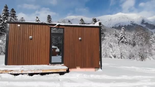 Vista aérea de uma casa inovadora de alta tecnologia com paredes espelhadas em meio a uma floresta de inverno nas montanhas. O conceito de ecoturismo nas montanhas. Arquitetura moderna em reservas naturais — Vídeo de Stock