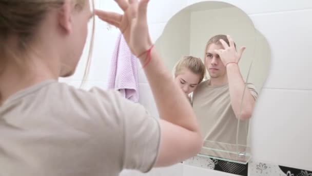 Una joven pareja atractiva hombre y una mujer con el pelo largo se pusieron en orden por la mañana en el baño. El concepto de familia joven y matrimonio civil — Vídeos de Stock