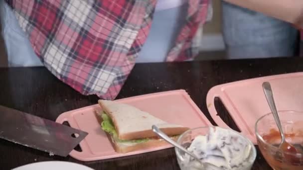 Primer plano joven pareja hombre y mujer hacer sándwiches en su cocina. El concepto de comidas caseras por su cuenta. Pelo largo moda chico y chica en la cocina — Vídeos de Stock