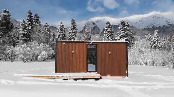 Αεροφωτογραφία καινοτόμου σπιτιού υψηλής τεχνολογίας με καθρεφτισμένους τοίχους μέσα σε χειμερινό δάσος στα βουνά. Η έννοια του οικολογικού τουρισμού στα βουνά. Σύγχρονη αρχιτεκτονική στα φυσικά καταφύγια — Αρχείο Βίντεο