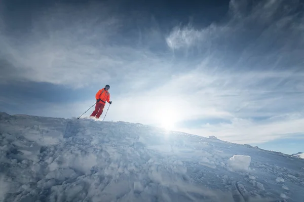 Atleta masculino esquiador salta de uma encosta coberta de neve contra o pano de fundo de uma paisagem montanhosa de montanhas cobertas de neve em um dia ensolarado. O conceito de esportes de inverno grande ângulo — Fotografia de Stock