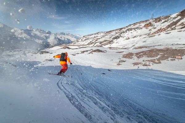 Lyžař jezdí na zasněženém svahu za slunečného dne při západu slunce na pozadí hor. Koncept zimního lyžování — Stock fotografie