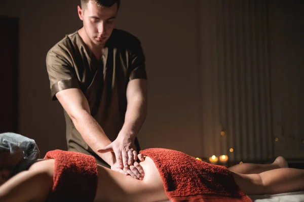 Cosmetologie en fysiotherapie. Professionele massage op de onderrug van een vrouw wordt gemaakt door een masseur man. Concept van manul therapie en massage spa behandelingen — Stockfoto