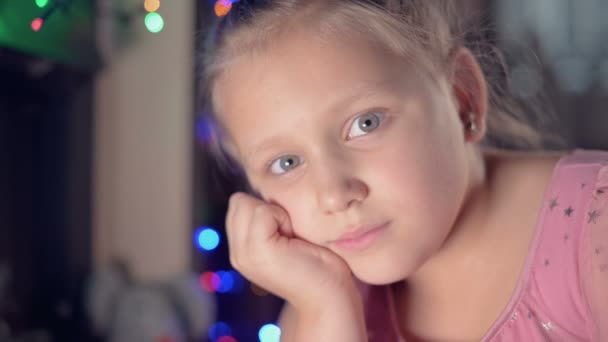 Ένα θλιμμένο κοριτσάκι με ροζ φόρεμα κοιτάζει την κάμερα. Χαλασμένες διακοπές. Ένα μελαγχολικό παιδί. — Αρχείο Βίντεο