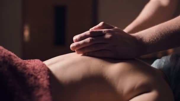 Massagem profissional das costas e parte inferior das costas. Massagem de massagista masculino um cliente para uma mulher em um quarto escuro à luz de velas — Vídeo de Stock