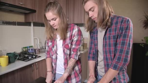 Ett ungt par gör smörgåsar i köket. Begreppet hemlagad mat på egen hand. Skär kött och grönsaker tillsammans till smörgåsar — Stockvideo