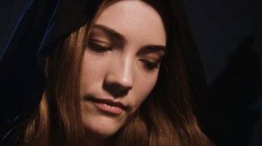 Çekici beyaz bir kadının yakın plan portresi. Siyah başlıklı, sarı saçlı, büyüleyici ve kur yapan bir kadın. Aşkın büyüsü ve Cadılar Bayramı konsepti