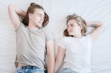 Üst tablolarda uzun saçlı bir çift kadın ve erkek yatakta tehlikeye girip birbirlerine bakıyorlar. Genç ailelerde sağlıklı seks ve mutluluk kavramı