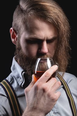 Stüdyoda, elinde bir bardak şarap ya da konyakla şık bir saç kesimi ve pantolon askısı olan şık bir adamın portresi..