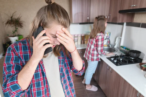 Alteración grave joven de pelo largo de pie en la cocina utiliza su teléfono móvil o pedir un servicio de Internet hablando por teléfono — Foto de Stock