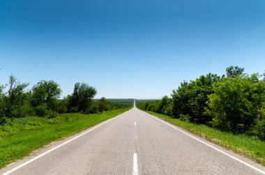 Yazın asfalt yolda yol kenarlarında mavi gökyüzüne karşı yeşil çimenler ve ağaçlar vardı. Ulaşım ve ulaşım lojistik şirketleri için güneşli bir gün.