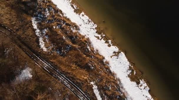 Flygfoto över strandlinjen en varm vinterdag. Gult gräs och snö på stranden. Begreppet global uppvärmning. Vidarebefordran — Stockvideo