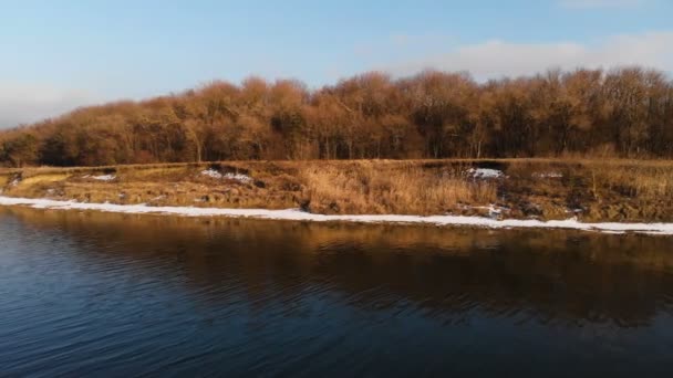 Vista aérea de la orilla del lago en parte en la nieve al atardecer. El concepto de embalses locales en temporada baja — Vídeo de stock