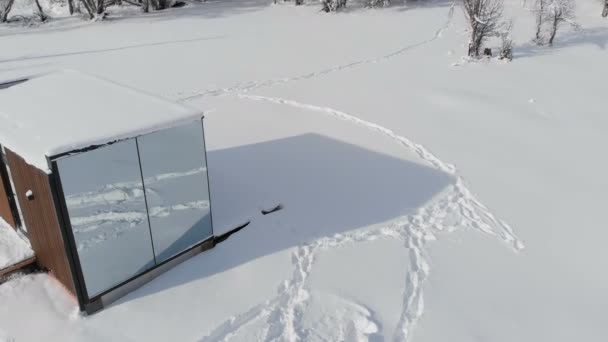 Widok z powietrza na innowacyjny dom high-tech z lustrzanymi ścianami pośród zimowego lasu w górach. Koncepcja ekoturystyki w górach. Nowoczesna architektura w rezerwatach przyrody — Wideo stockowe
