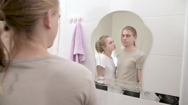 Un jeune couple séduisant et une femme aux cheveux longs se mettent en ordre le matin dans la salle de bain. La notion de jeune famille et de mariage civil — Video