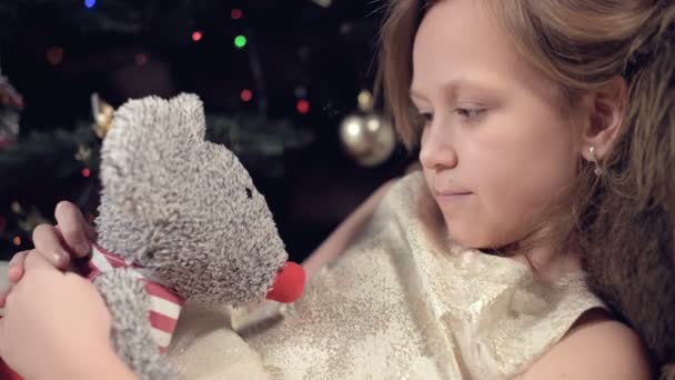 A sad little girl in a pink dress lonely looks at his stuffed toy. Spoiled holiday. A brooding child — Stock Video