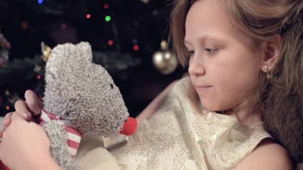 Una niña triste en un vestido rosa sola mira su juguete de peluche. Vacaciones malcriadas. Un niño melancólico — Vídeos de Stock