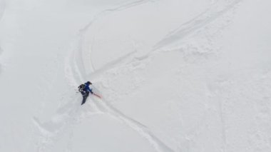 Dik bir yamaca tırmanan erkek bir kayakçının hava manzarası. Kuzey Kafkasya 'nın yüksek dağlarında kayaklarla kayak yaparak Skitour beleşçilik yapıyor.