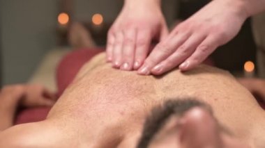 Erkek masör, profesyonel masaj salonundaki sporcu sporcuya göğüs kası masajı yapıyor. Göğüs kası ve göğüs kası sağlığı kavramı.