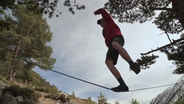 北コーカサスの山々のスラックラインで若い男が歯を食いしばっています。山の背景にスラックライン — ストック動画