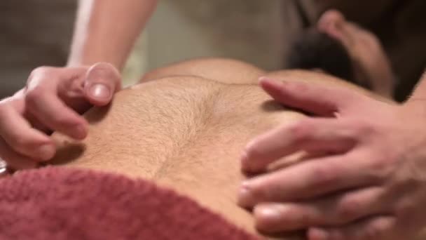 Um homem massageador fisioterapeuta ativa uma massagem diafragmática para um atleta masculino cliente muscular. Close-up. Pequena profundidade de campo — Vídeo de Stock