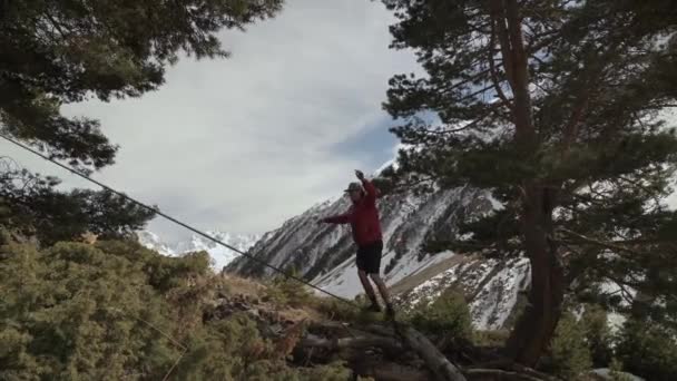 Ένας νεαρός άνδρας παραπαίει σε μια χαλαρή γραμμή στα βουνά του Βόρειου Καυκάσου. Slackline en φόντο των βουνών — Αρχείο Βίντεο