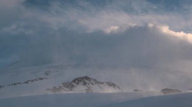 Zaman eğrisi, günbatımından önce rüzgarlı ve karlı bulutların güney ladin hareketidir. Kar ile yüksek irtifa zaman ayarlı. Dağlarda hava değişiyor.
