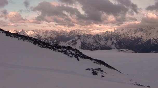 El crepúsculo del timelapse de gran altitud con una puesta de sol rosa después de la puesta de sol en lo alto de las montañas del norte del Cáucaso. Picos de nieve con nubes — Vídeos de Stock