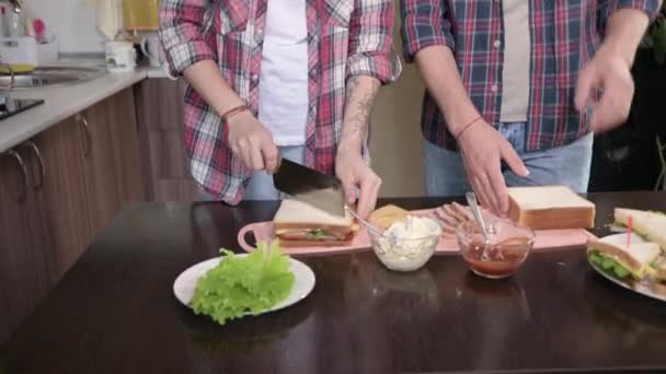 Ein junges Paar backt in der Küche Sandwiches. Das Konzept der selbstgekochten Mahlzeiten. Langhaarige Mode Typ und Mädchen in der Küche — Stockvideo